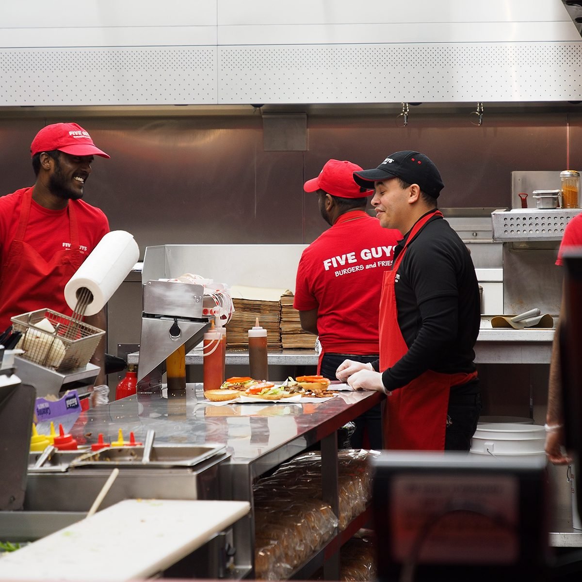 Closeup of crews working at Five Guys burger chain busily, Avenue des Champs-Élysées, Paris, France