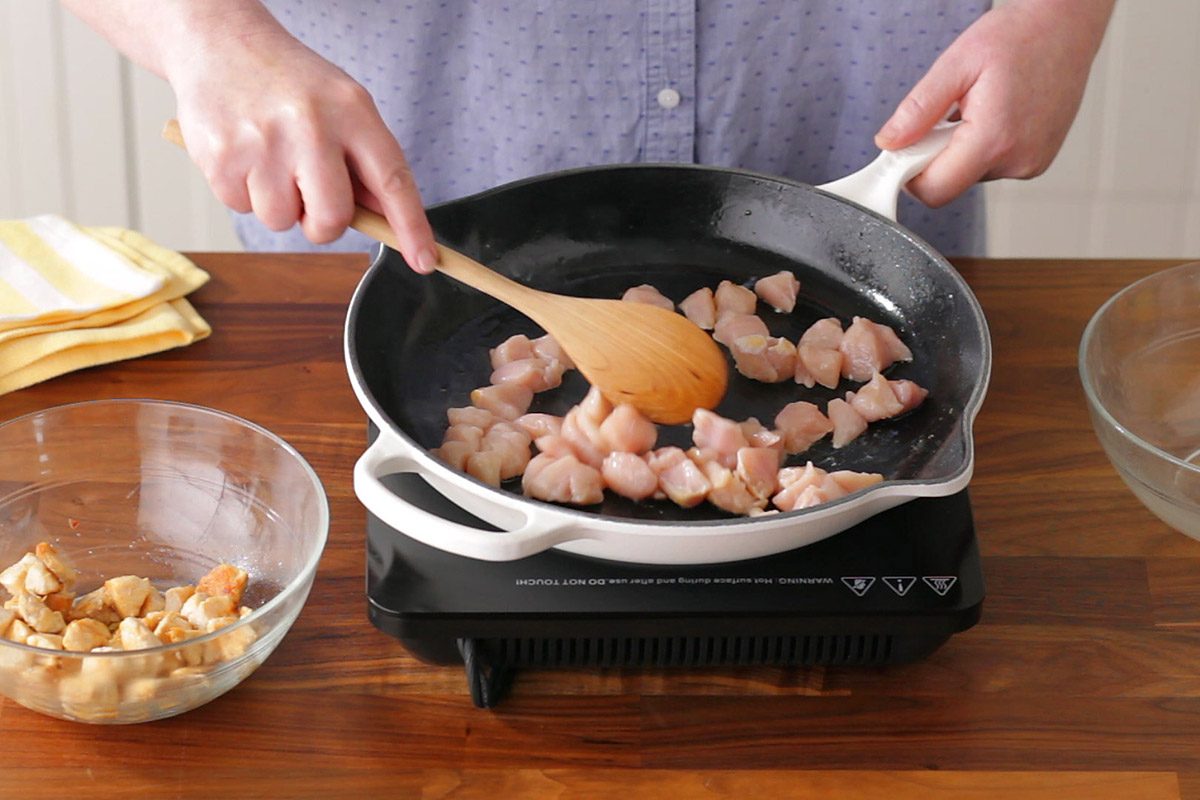 person browning meat in a pan to make curry
