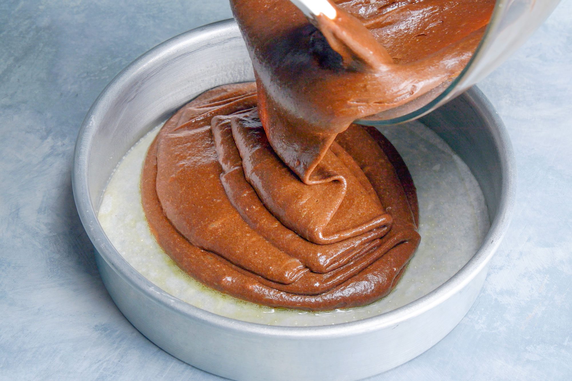 ingredients being poured into greased cake pan