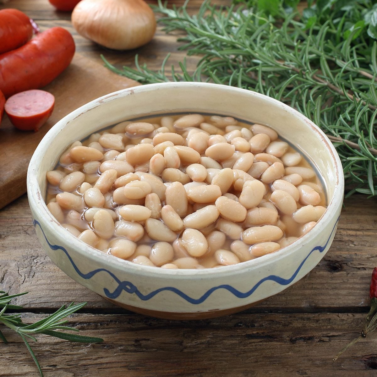 boiled white beans in ceramic bowl on a rustic chicken table background