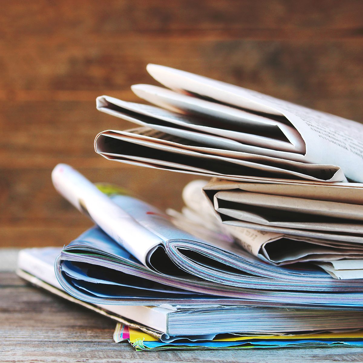 Newspapers and magazines on old wood background. 