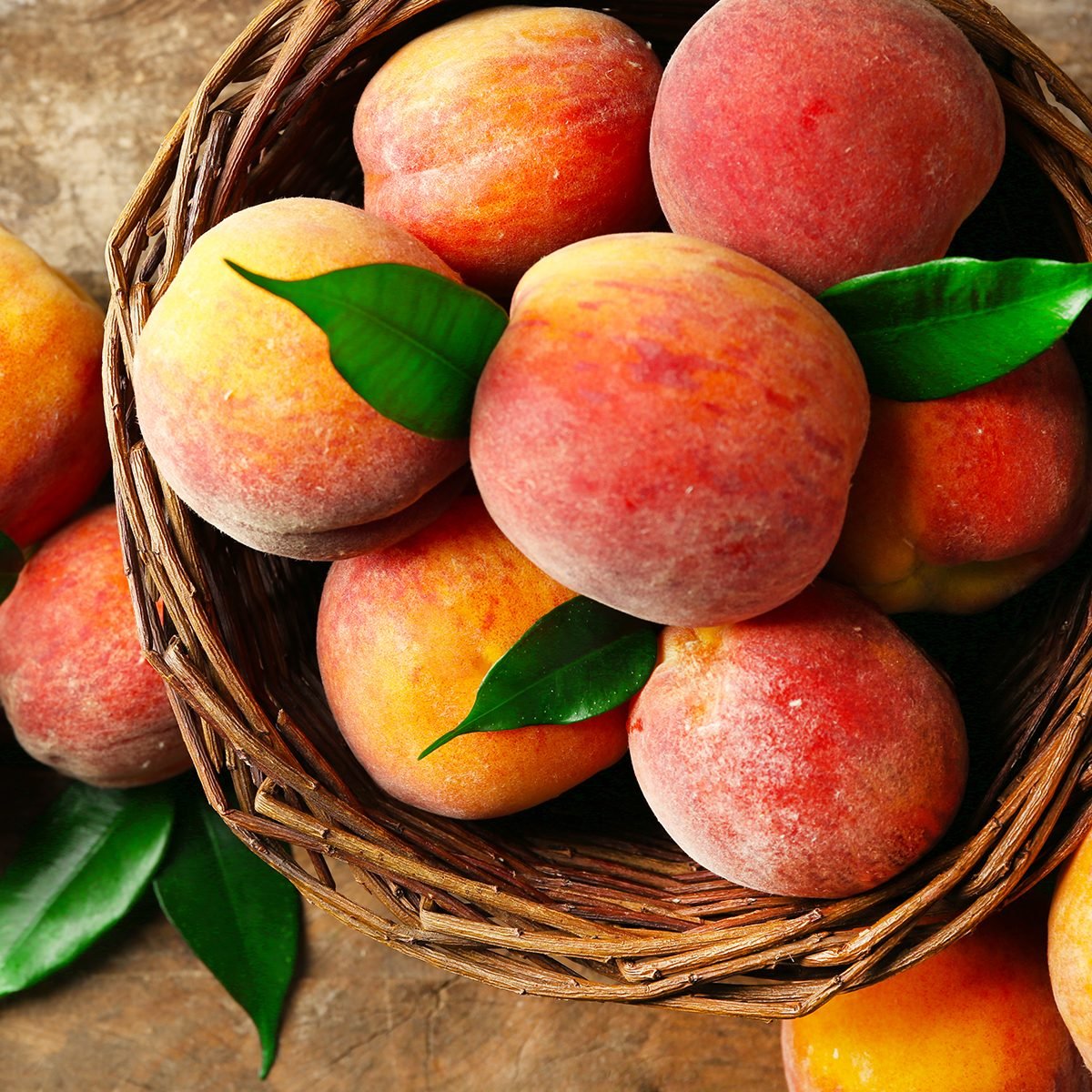 Ripe peaches in basket on wooden background