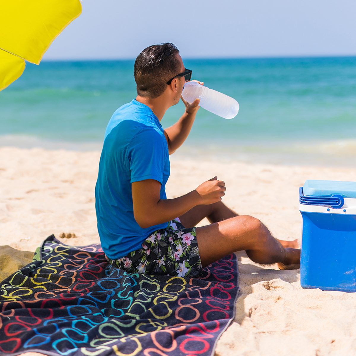 Young man under green solar umbrella drink water from cooler on beach; Shutterstock ID 668276848; Job (TFH, TOH, RD, BNB, CWM, CM): TOH