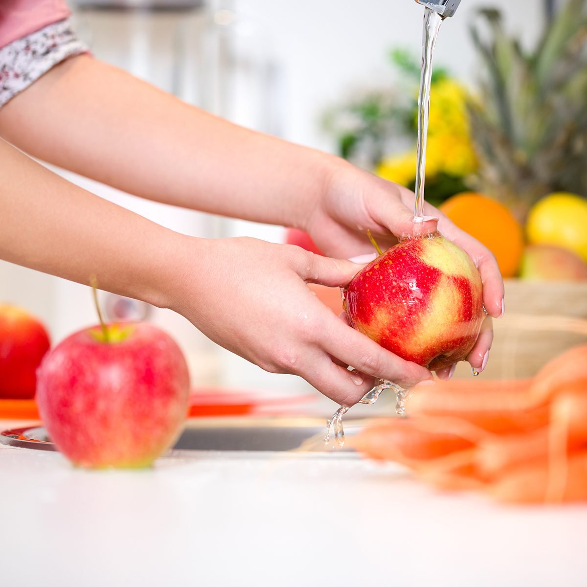 Woman hands washing tasty apple under the tap