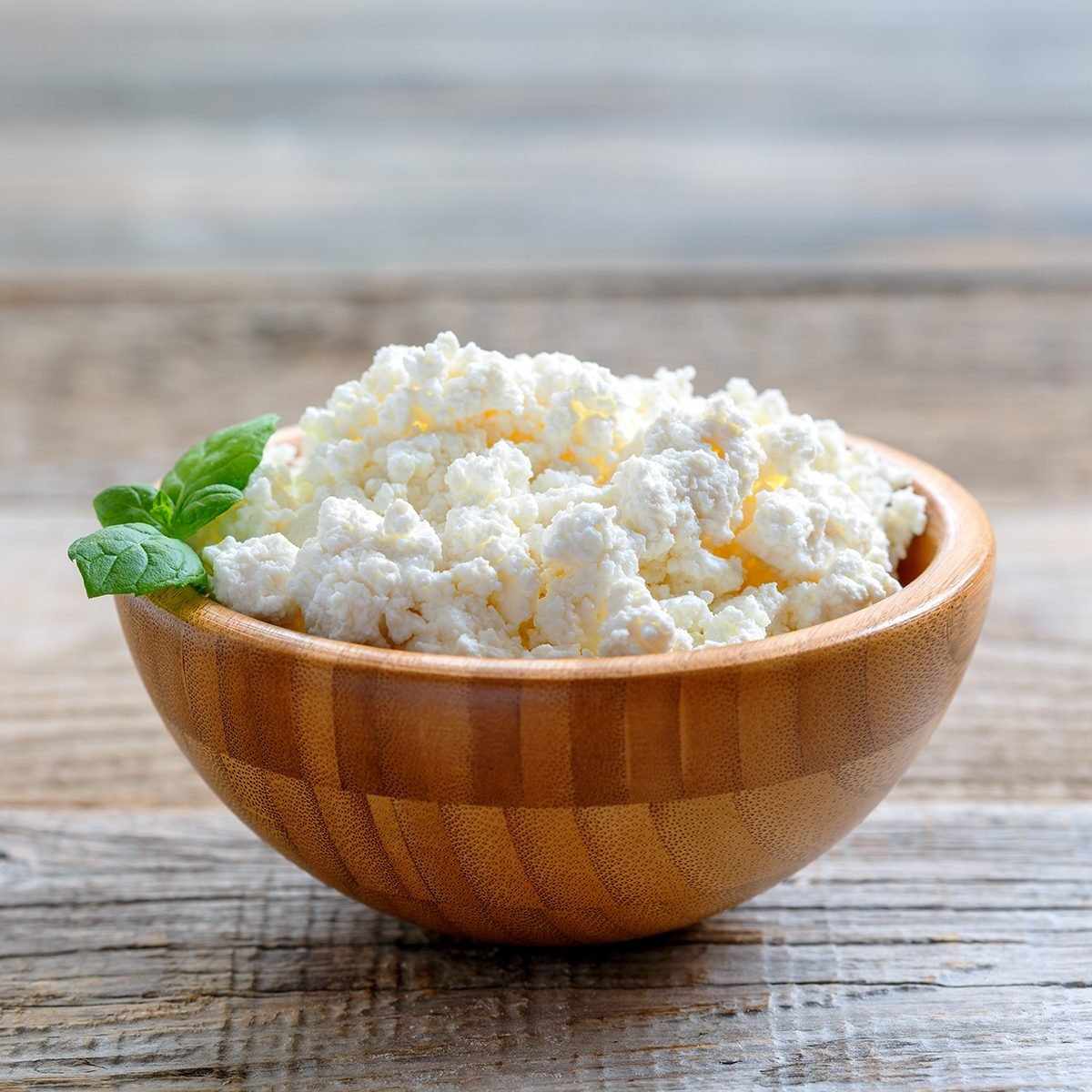 Homemade cottage cheese in a bowl on old wooden table.