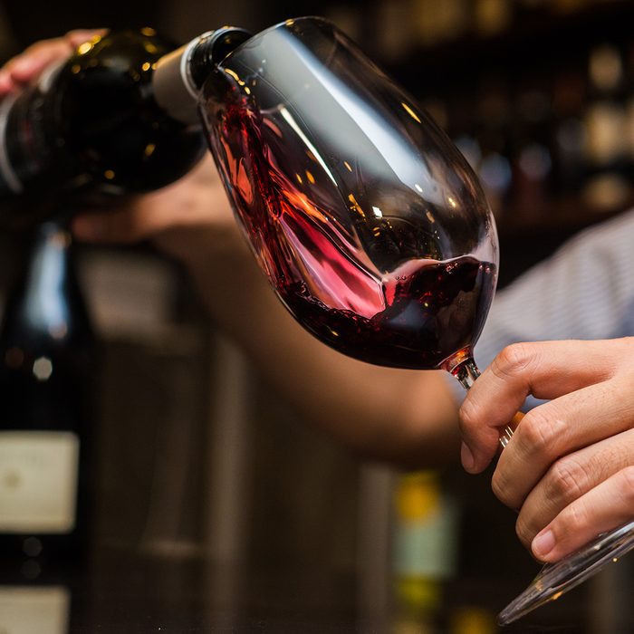 Waiter pouring red wine in a glass.