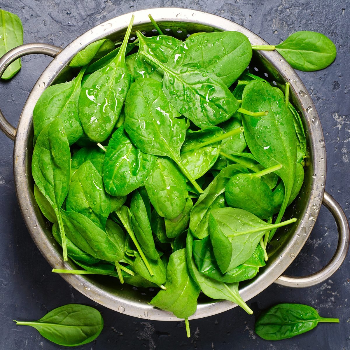 Washed fresh mini spinach in a colander on the old concrete table