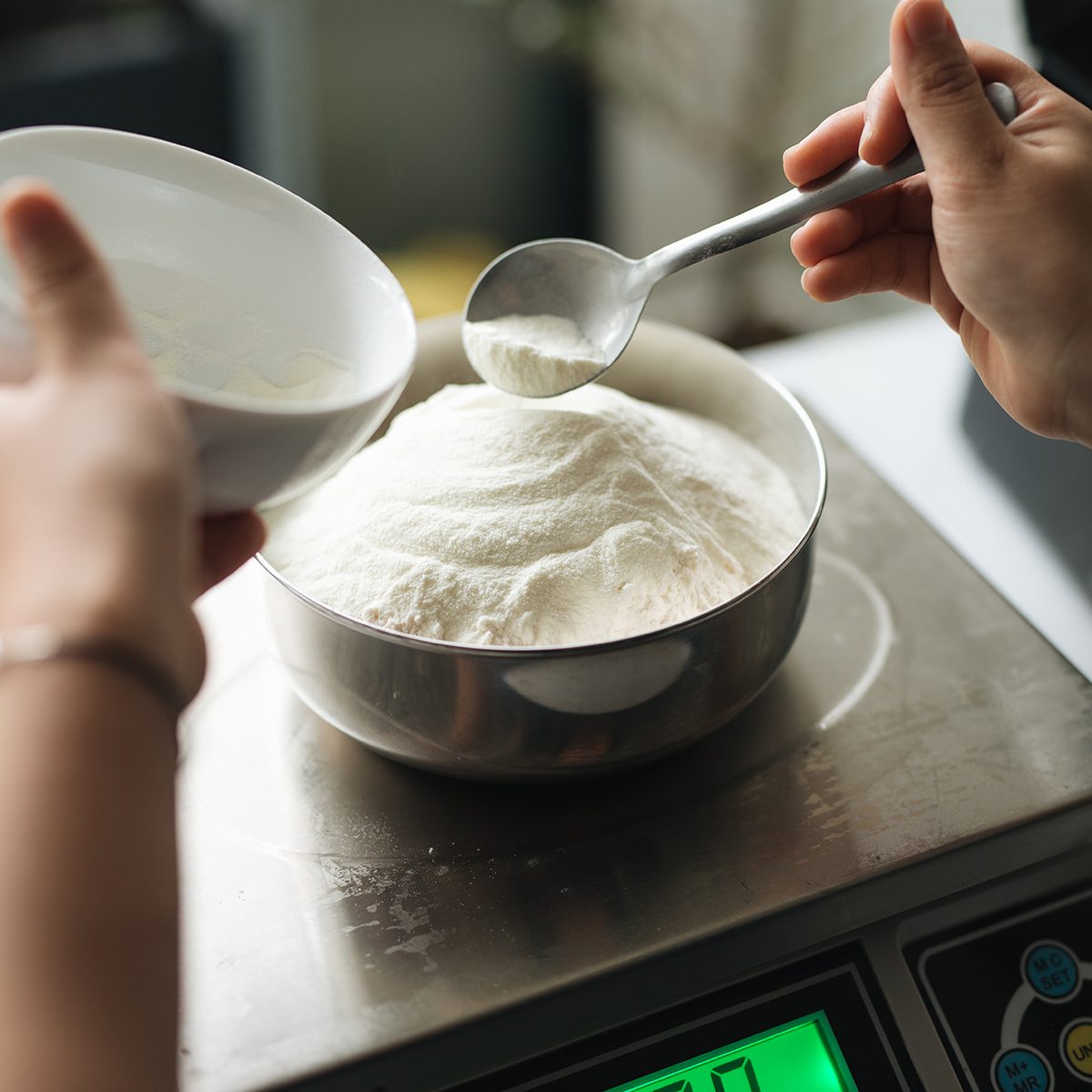 Bakery chef weighing flour on the digital scale