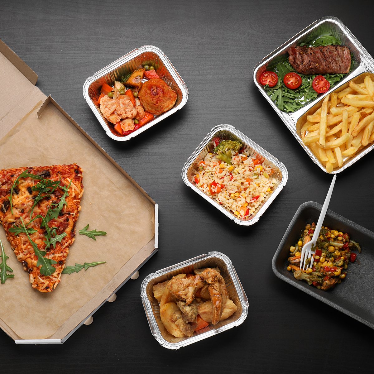 Different containers with delicious food on wooden table.