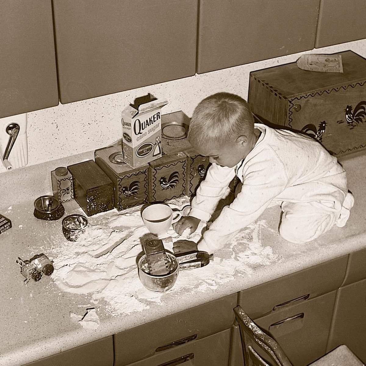 little boy making a mess with flour on the counter
