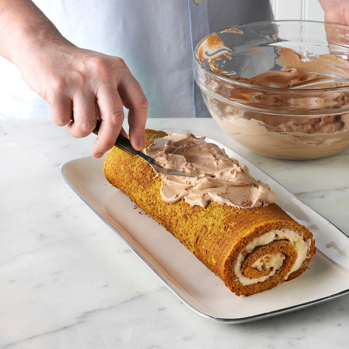 putting buttercream onto the outside of a cake