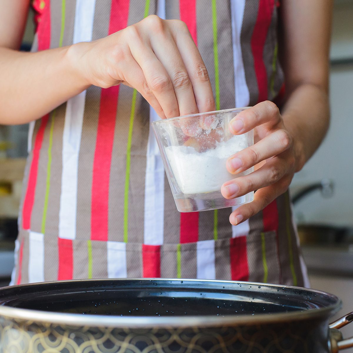 Cook takes cup of salt to water in bowl