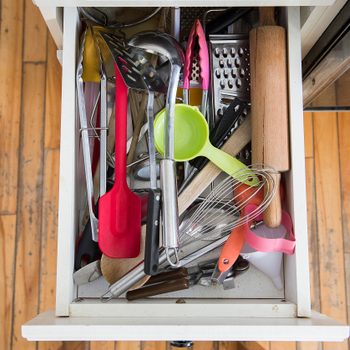 a kitchen drawer packed with utensils is shown