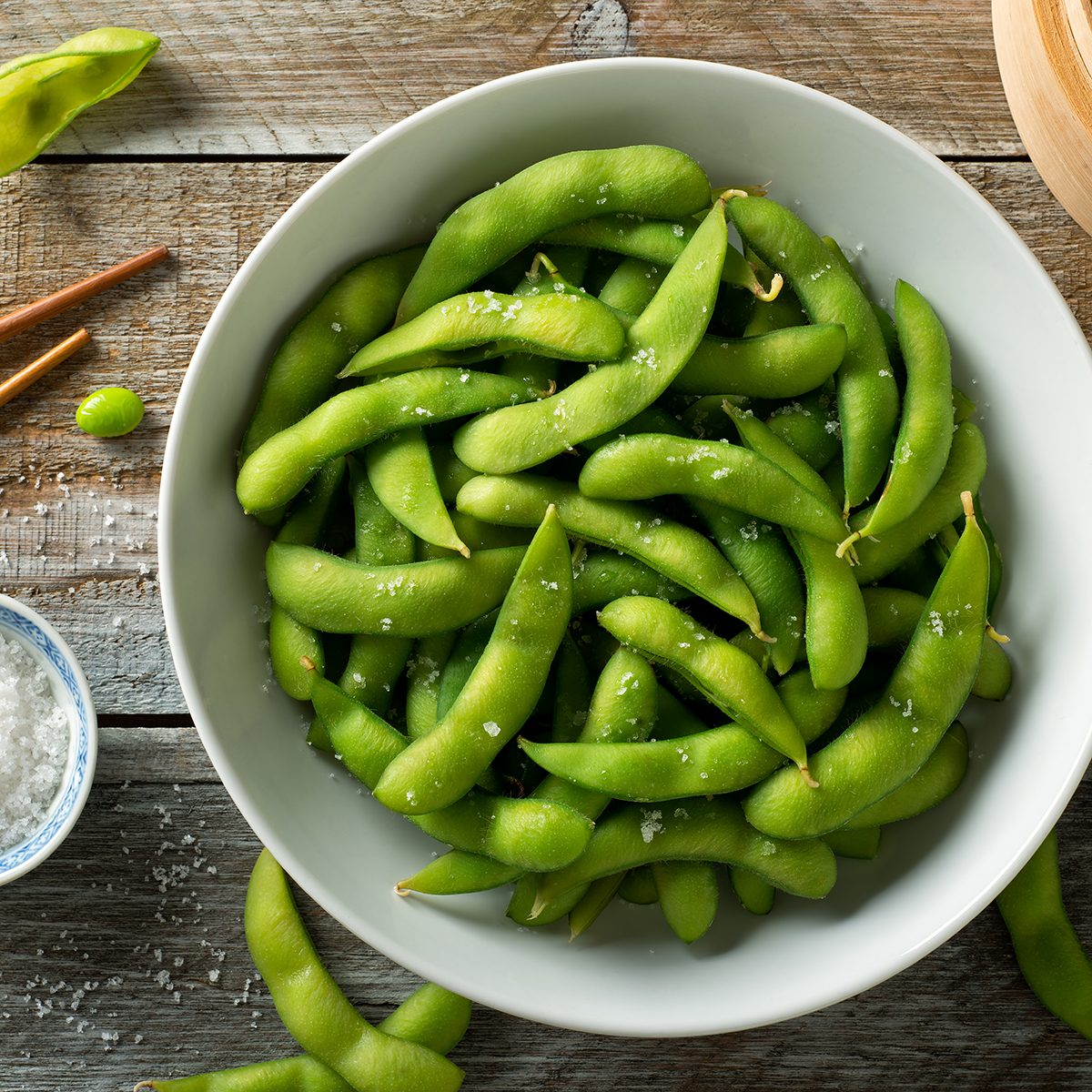 Fresh steamed edamame sprinkled with sea salt on a rustic tabletop.