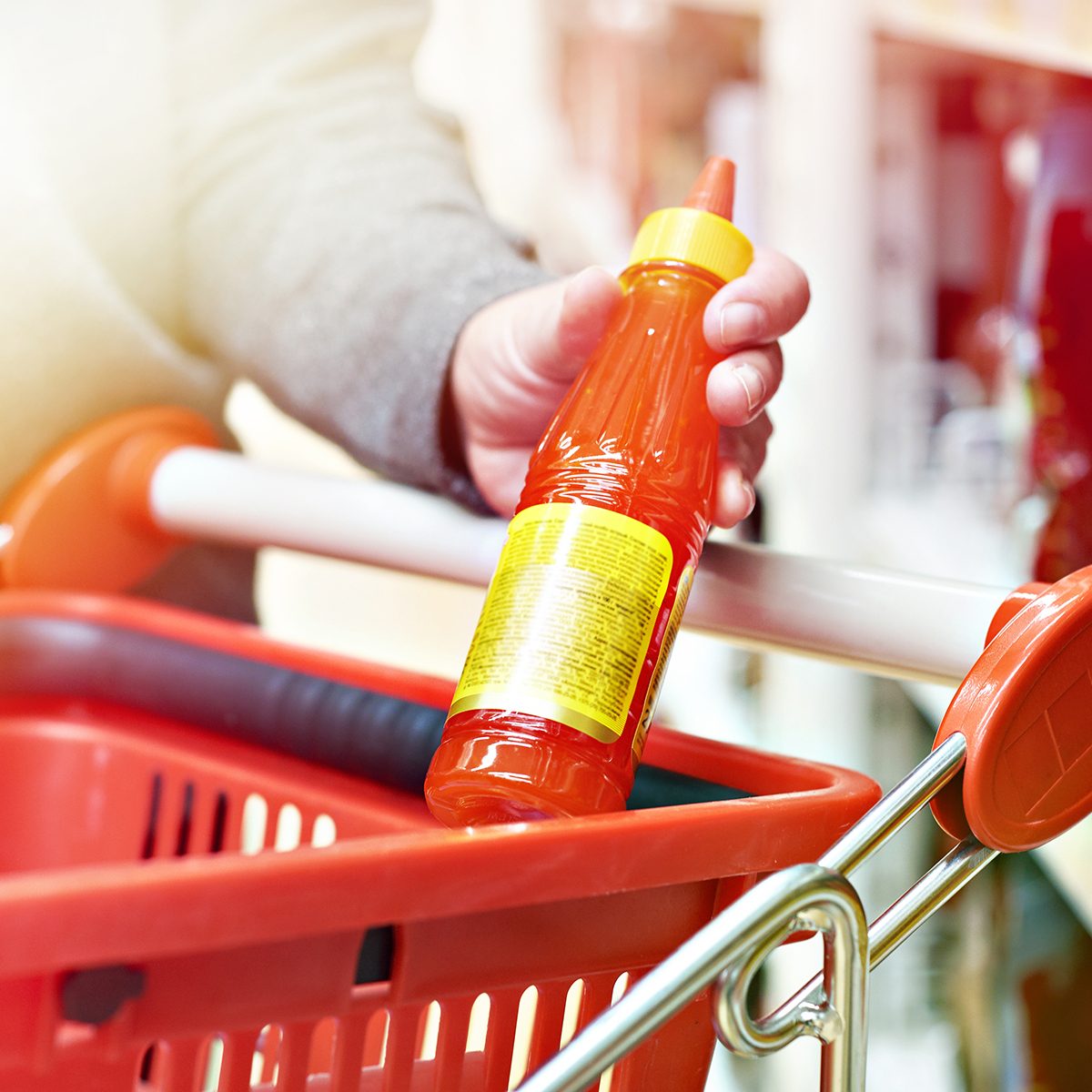 Hot chilli sauce in the hands of the buyer at the grocery store
