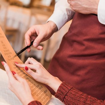 Cropped image of customer asking waiter about food in menu