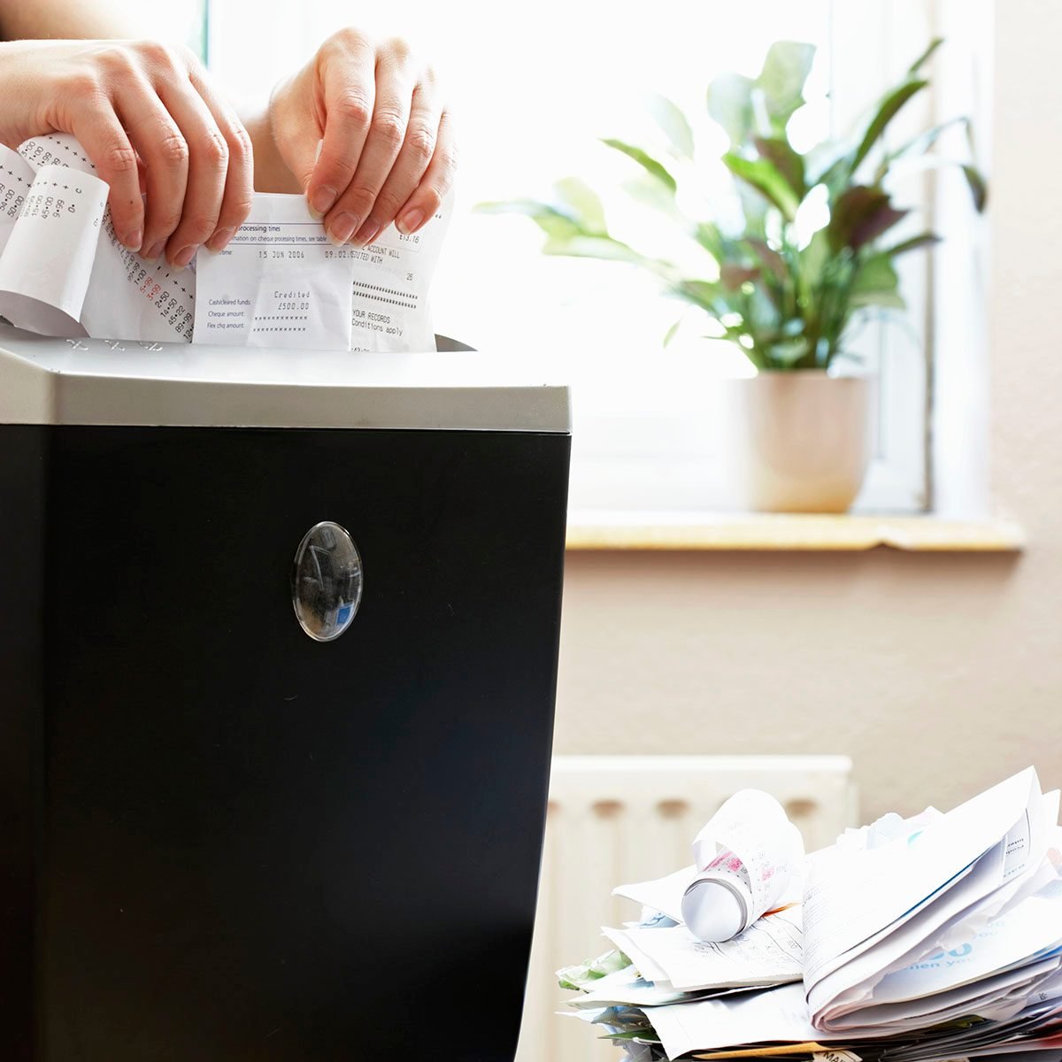 Woman shredding receipts in paper shredder, close-up