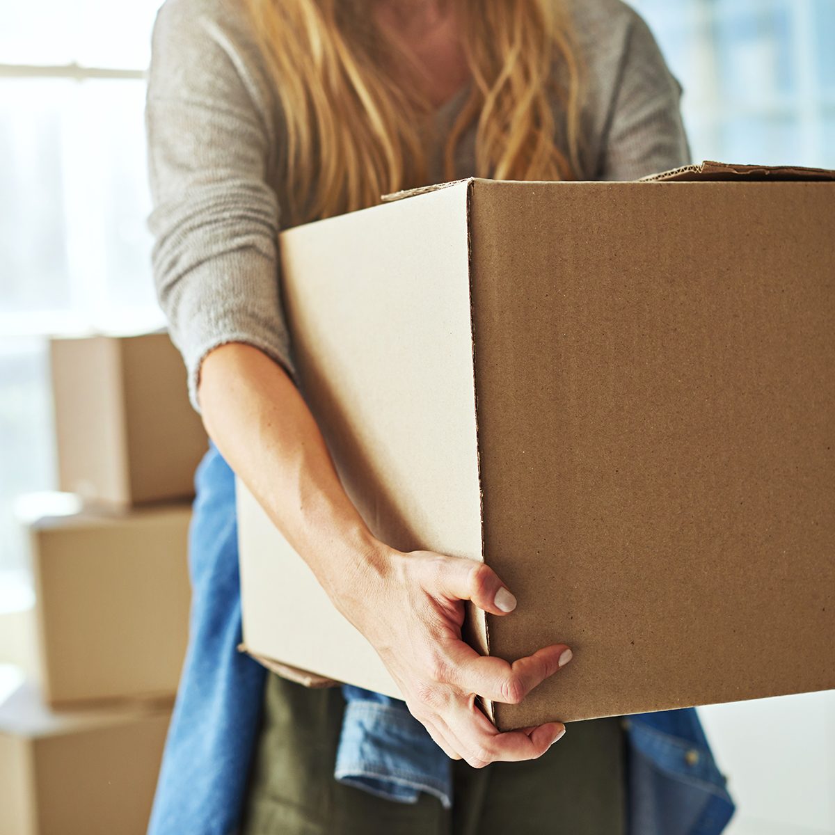 Cropped shot of a young woman carrying boxes while moving into her new home