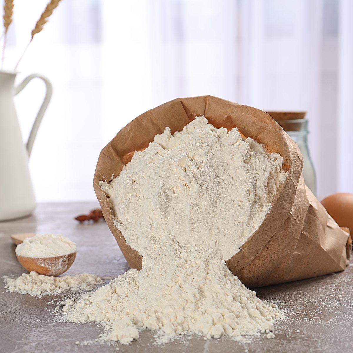 Paper bag and spoon with flour on table