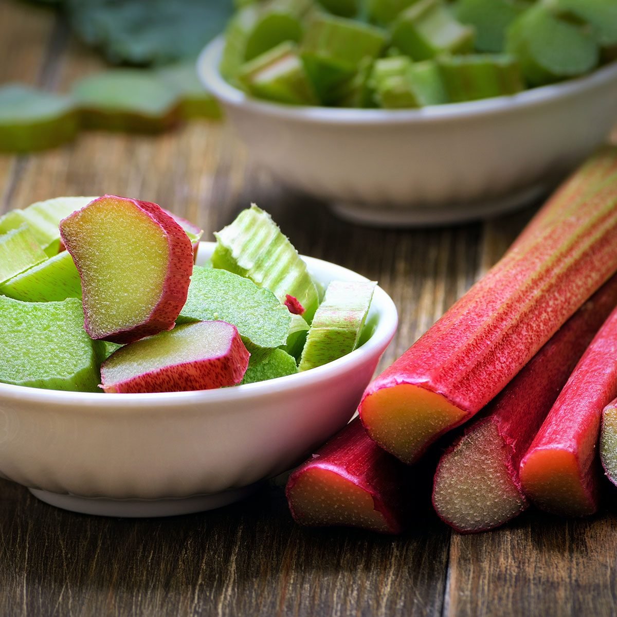 Fresh rhubarb in white bowl on wooden table