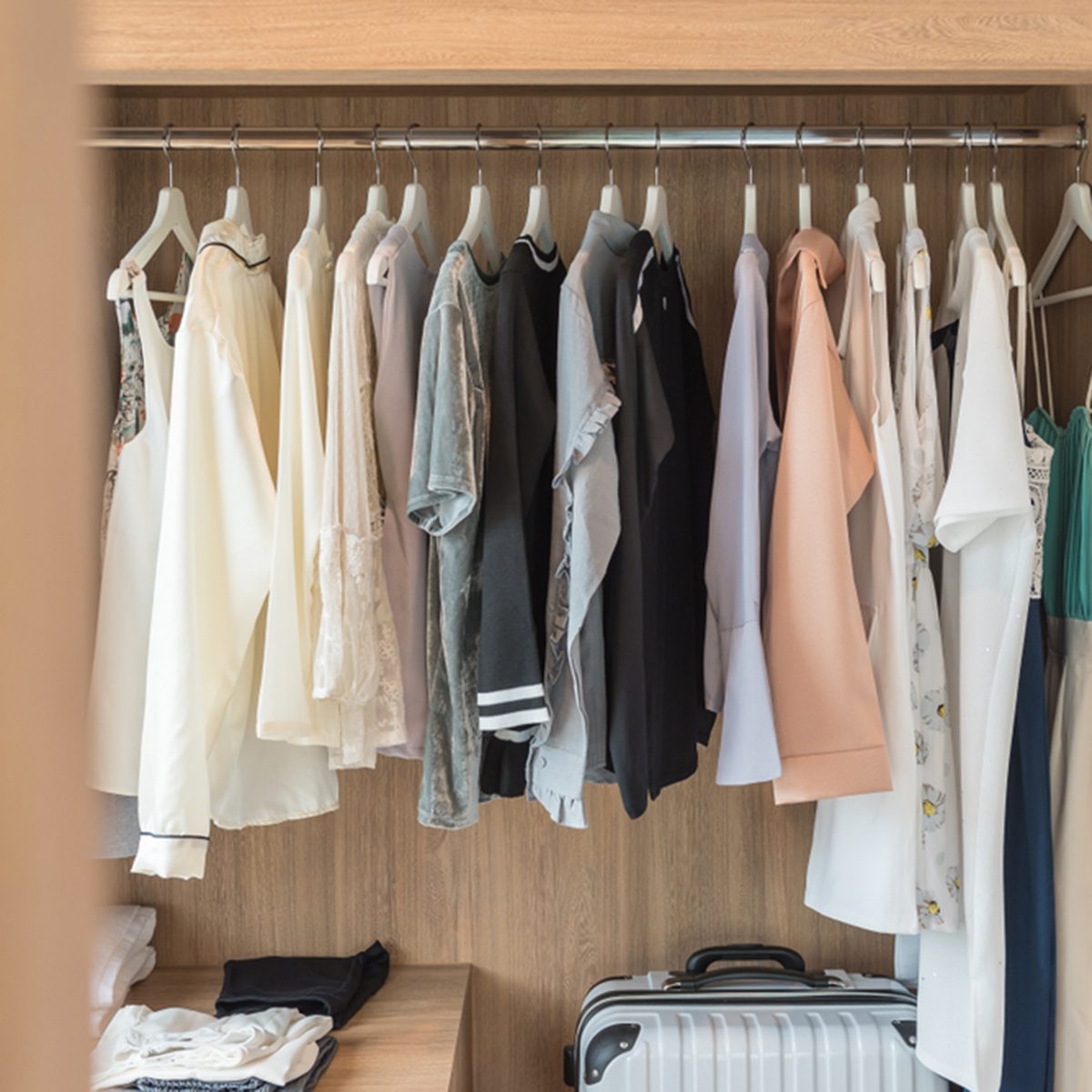 wooden closet with clothes hanging on rail, wardrobe interior design; Shutterstock ID 1012695814