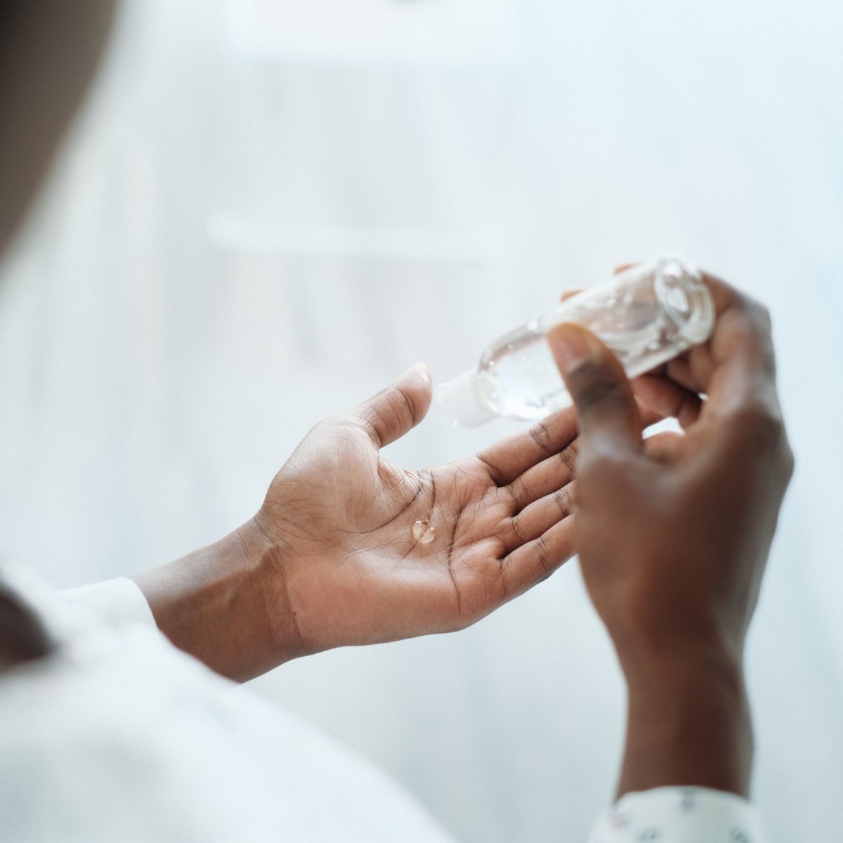 African American Woman Disinfecting Skin With Hand Sanitizer