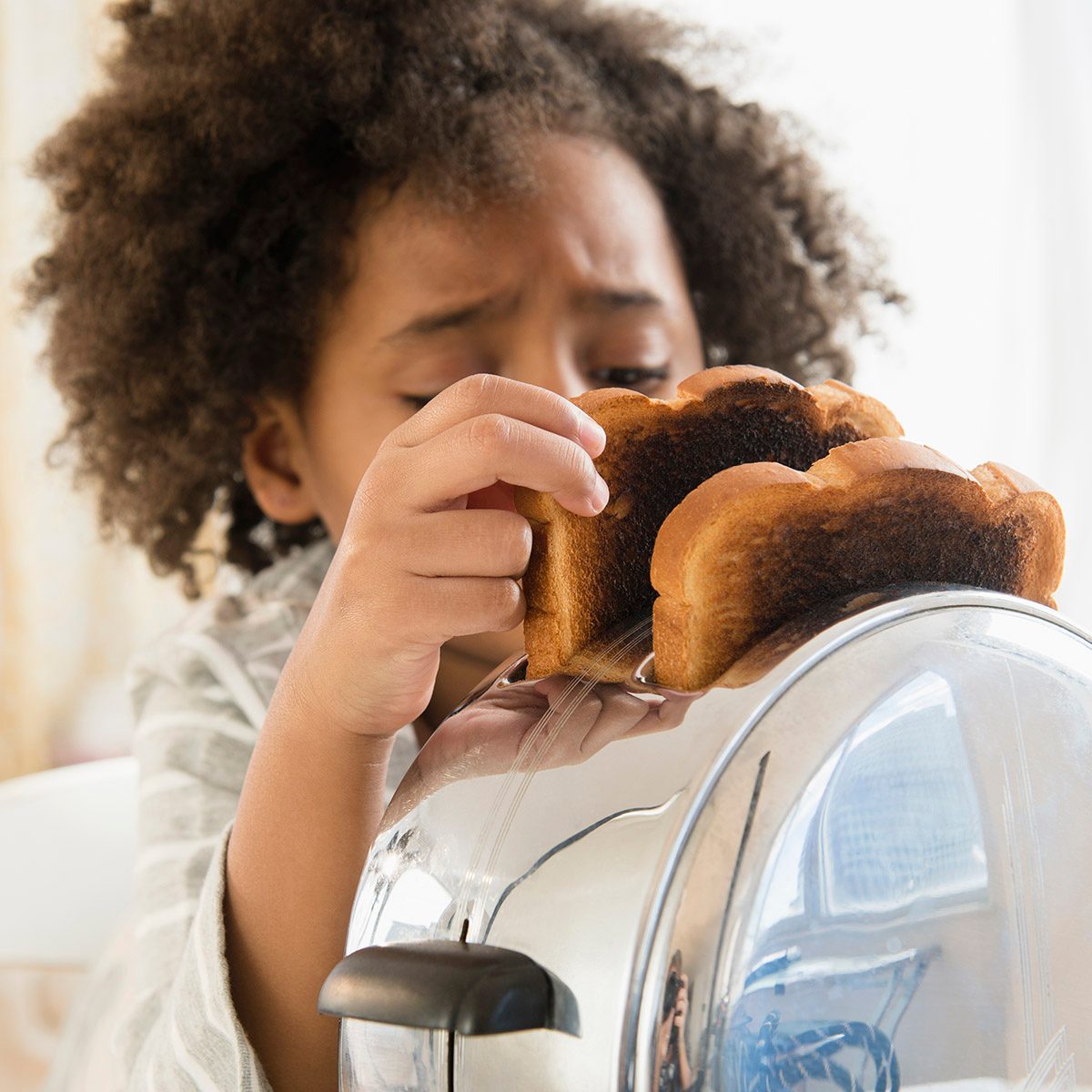 African American girl burning toast in toaster