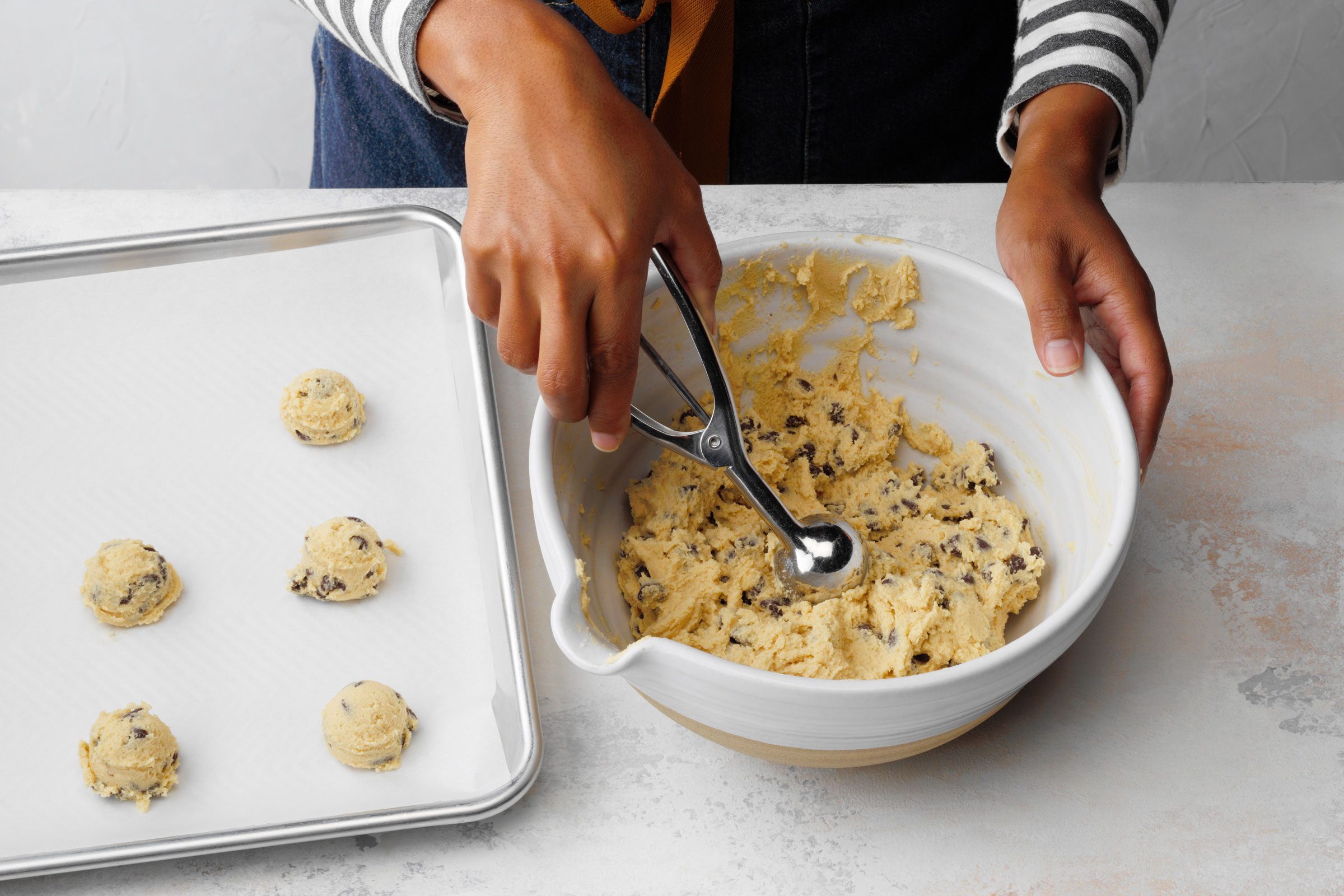 Gluten Free Chocolate Chip Cookies being shaped and placed on a baking sheet lined with parchment paper