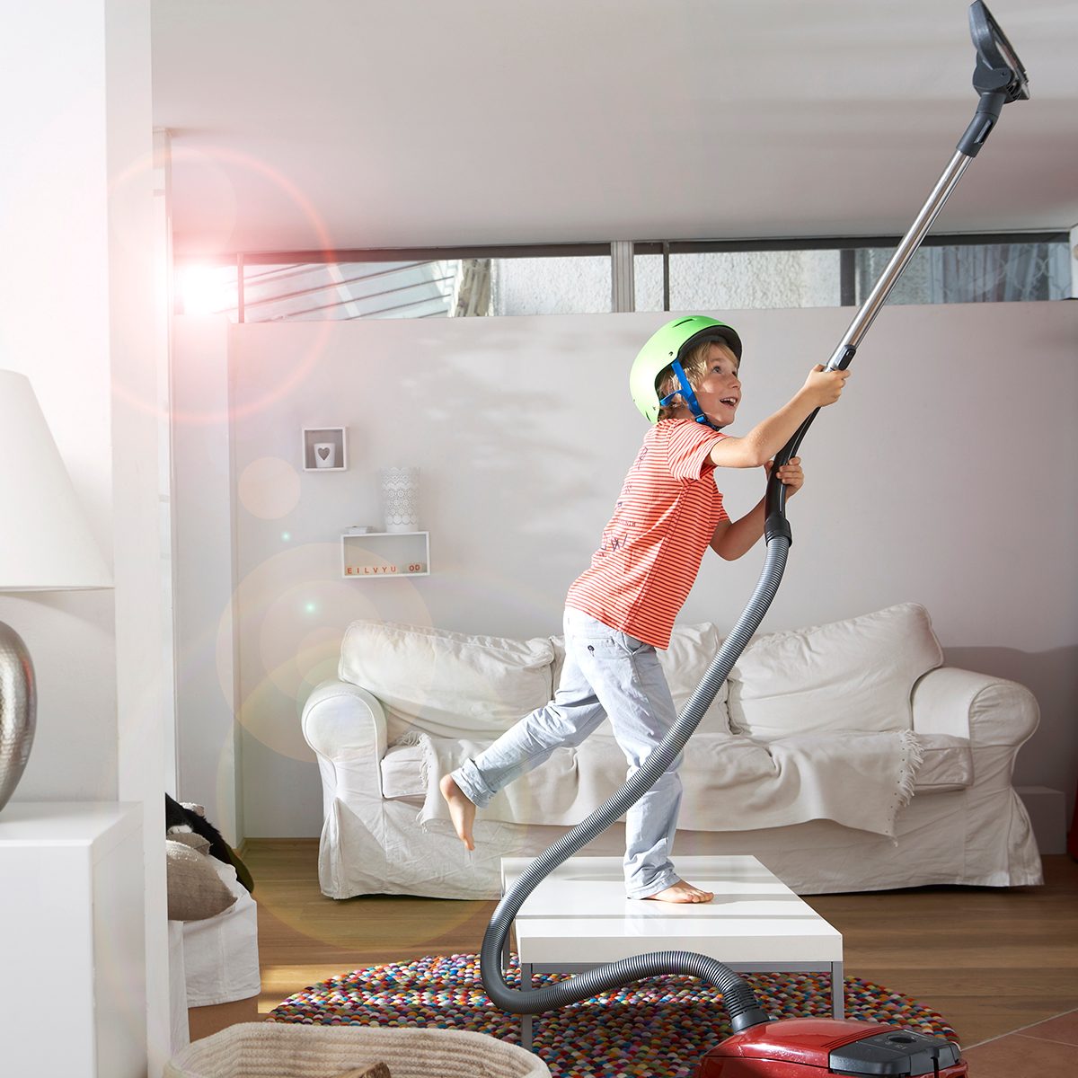 Boy In Living Room Hoovering The Ceiling