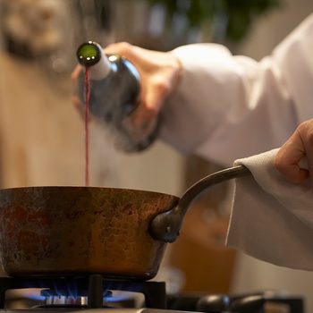 how to cook with wine Female Chef Pouring Wine Into Pan