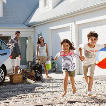 Brother And Sister With Beach Ball Running On Driveway