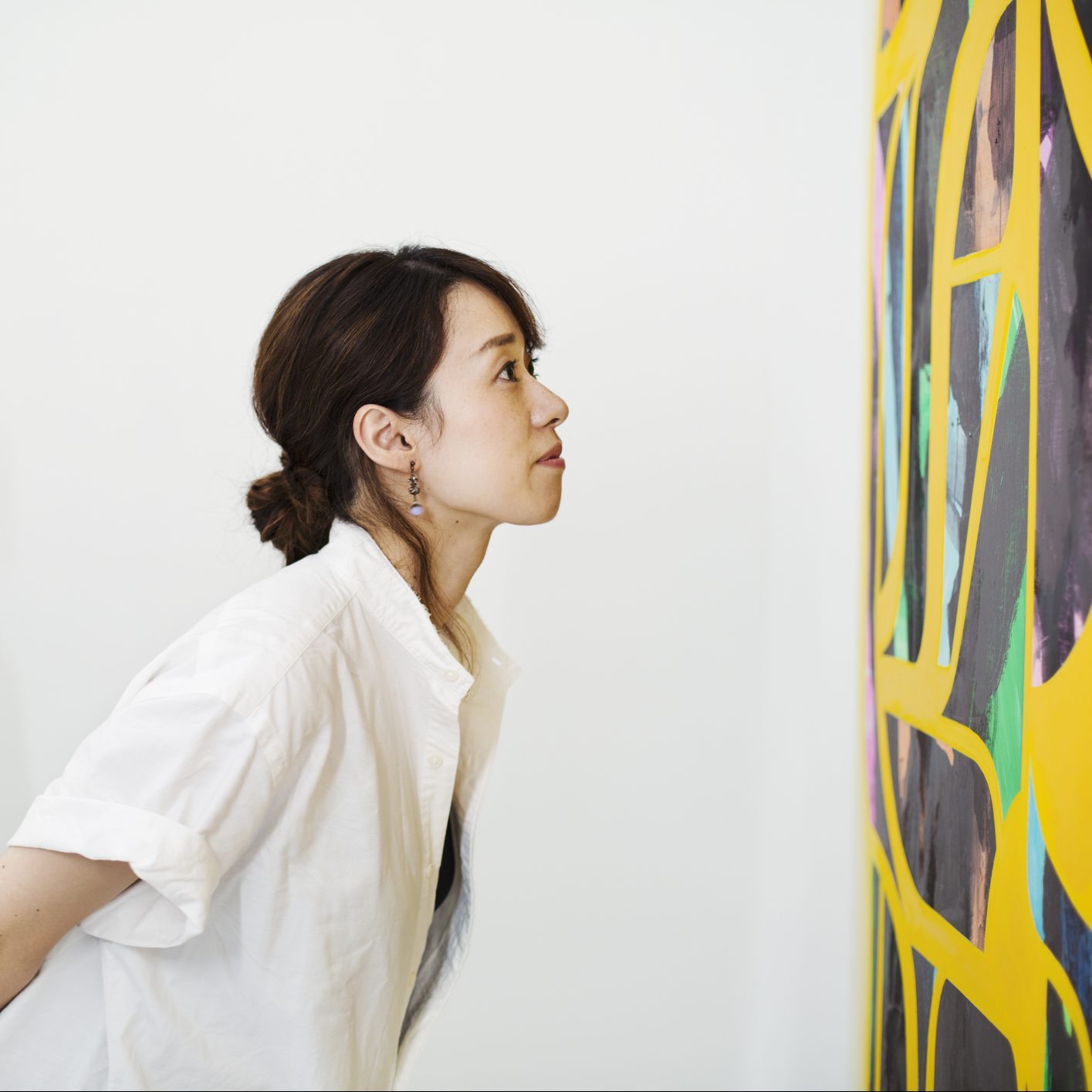 Two women standing in an art gallery, looking at an abstract modern painting.