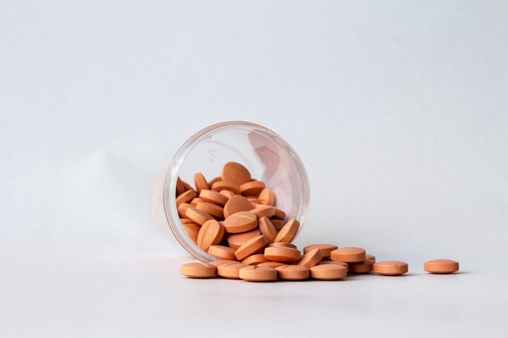 bottle of pills on a gray background with pills spilling out