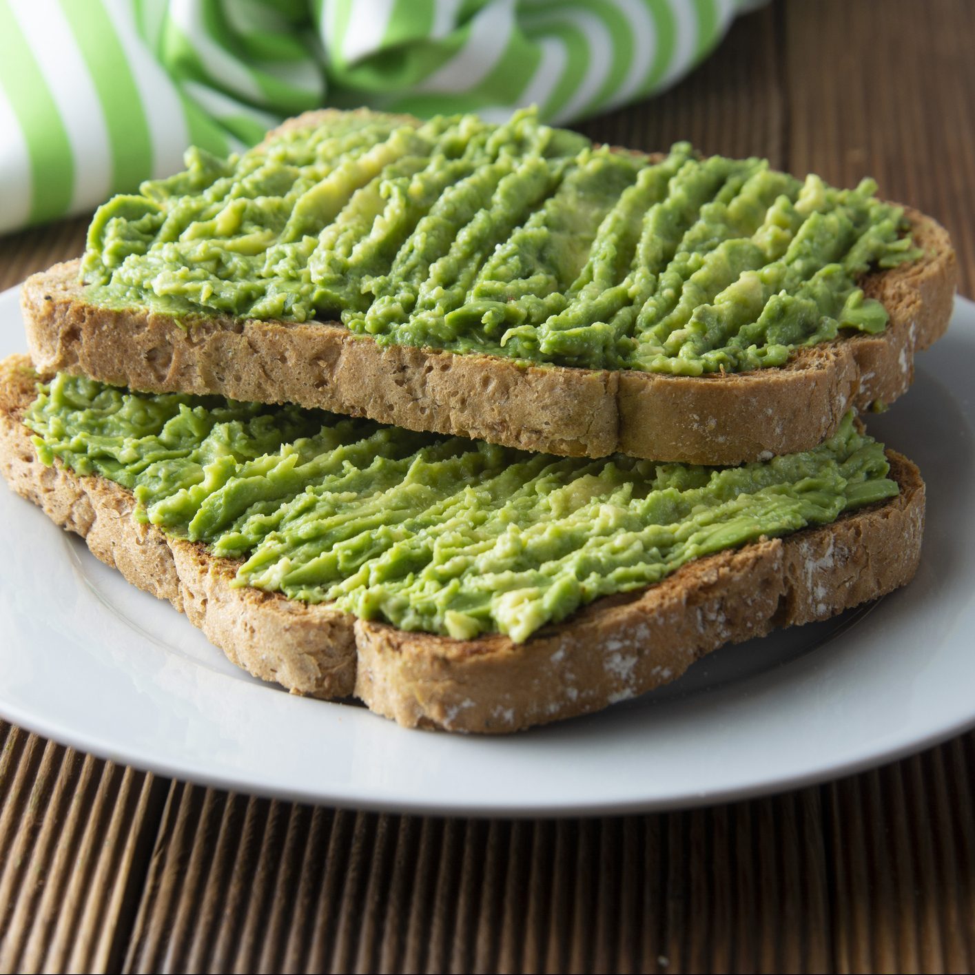 two pieces of avocado toast on a white plate