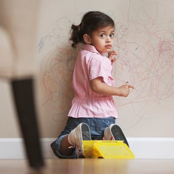 Hispanic girl drawing on wall