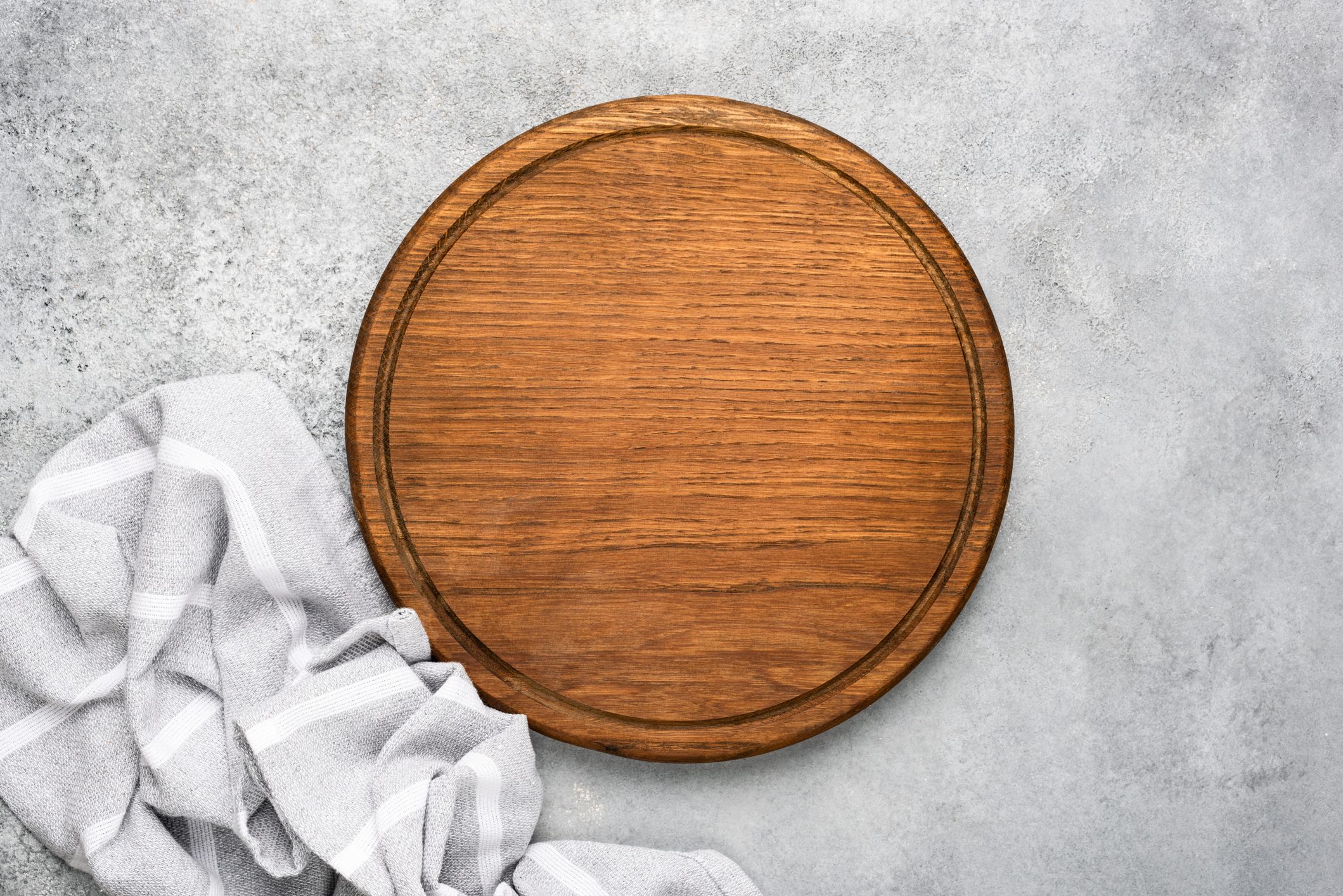 Round wooden cutting board on grey concrete background