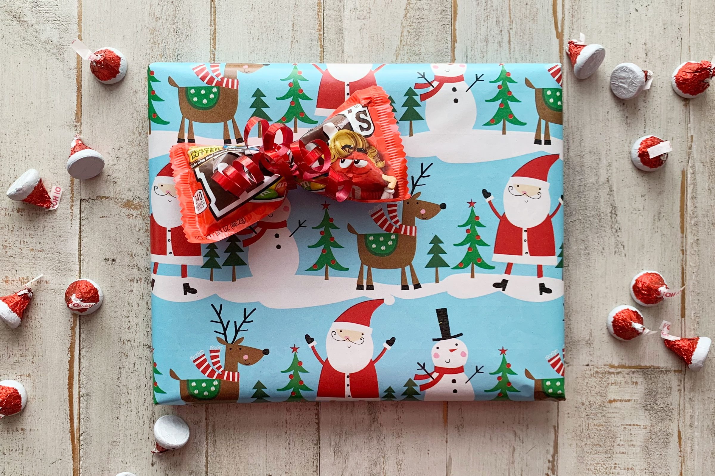 wrapped christmas gift with a pack of m&ms made into a bow