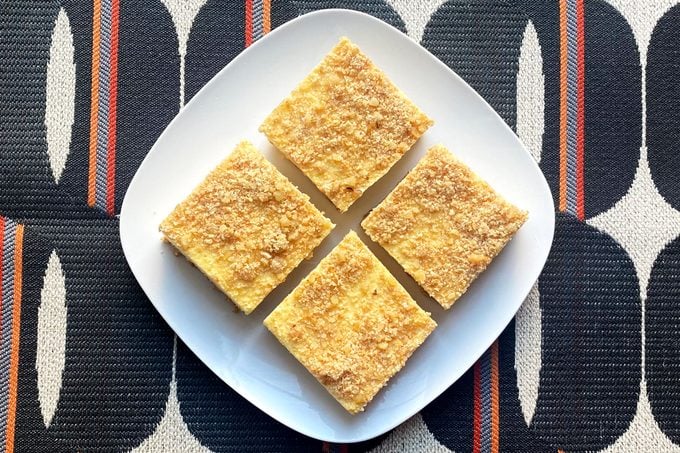 Creamy Pineapple Squares finished product on white plate sitting atop a retro tablecloth