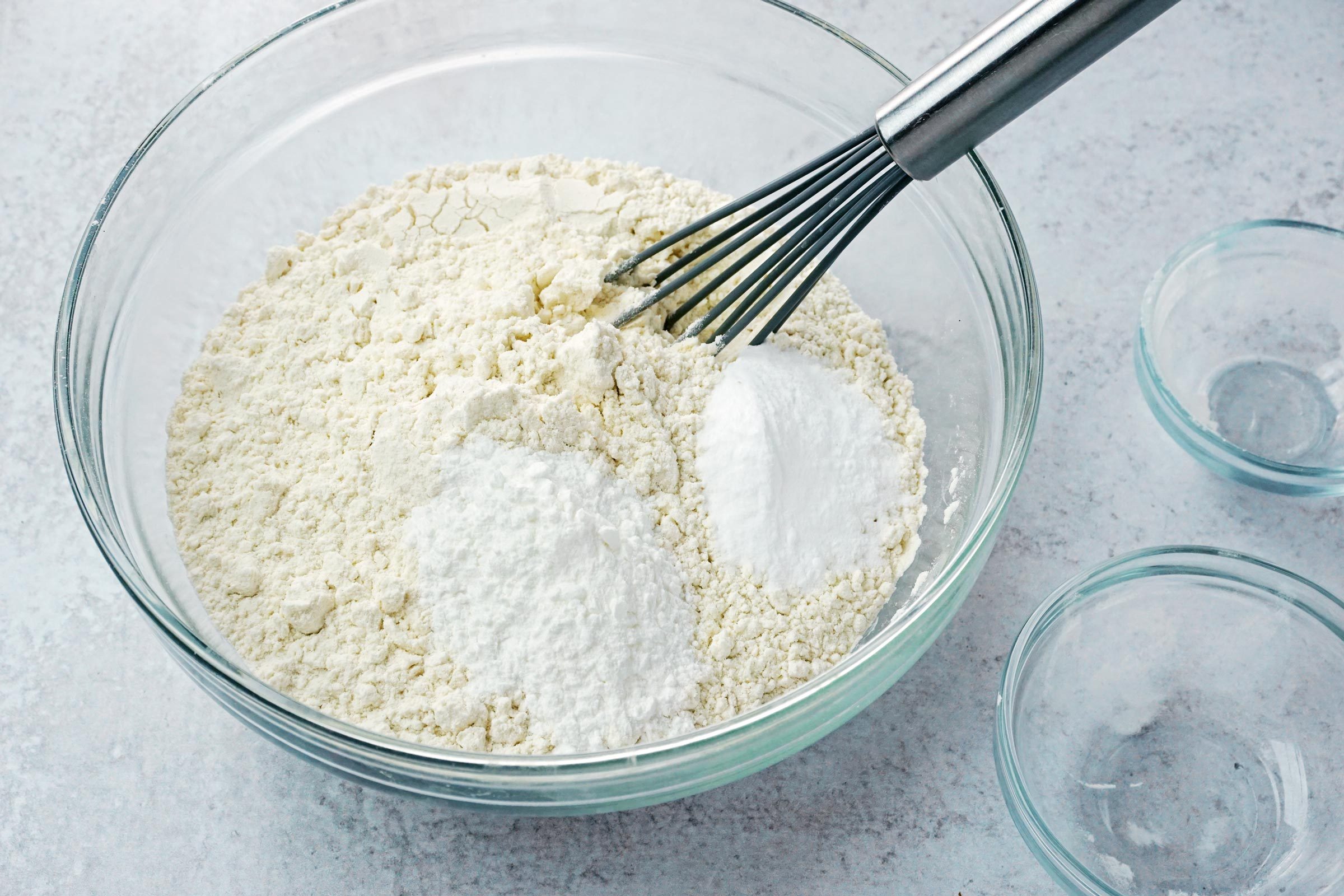 large glass bowl with dry ingredients for baking and a whisk