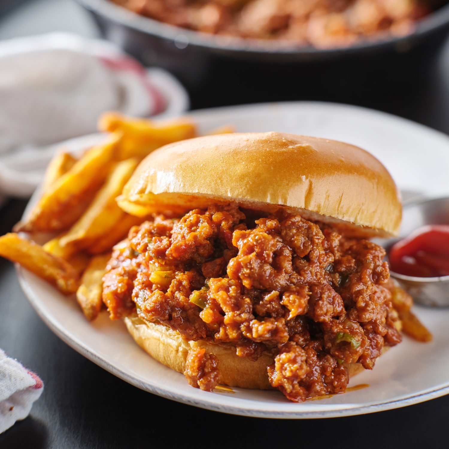 sloppy joe sandwich on plate with french fries and ketchup