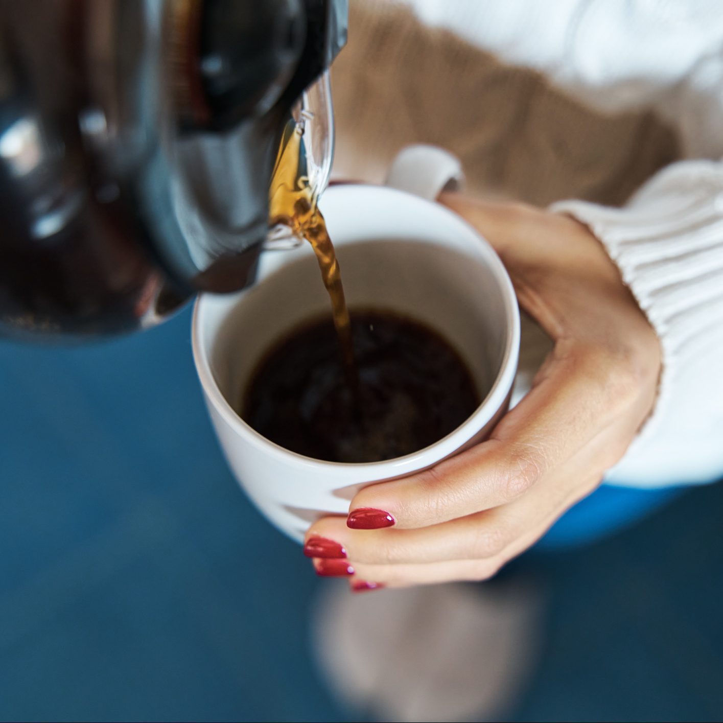 Woman pouring herself hot coffee to a mug.