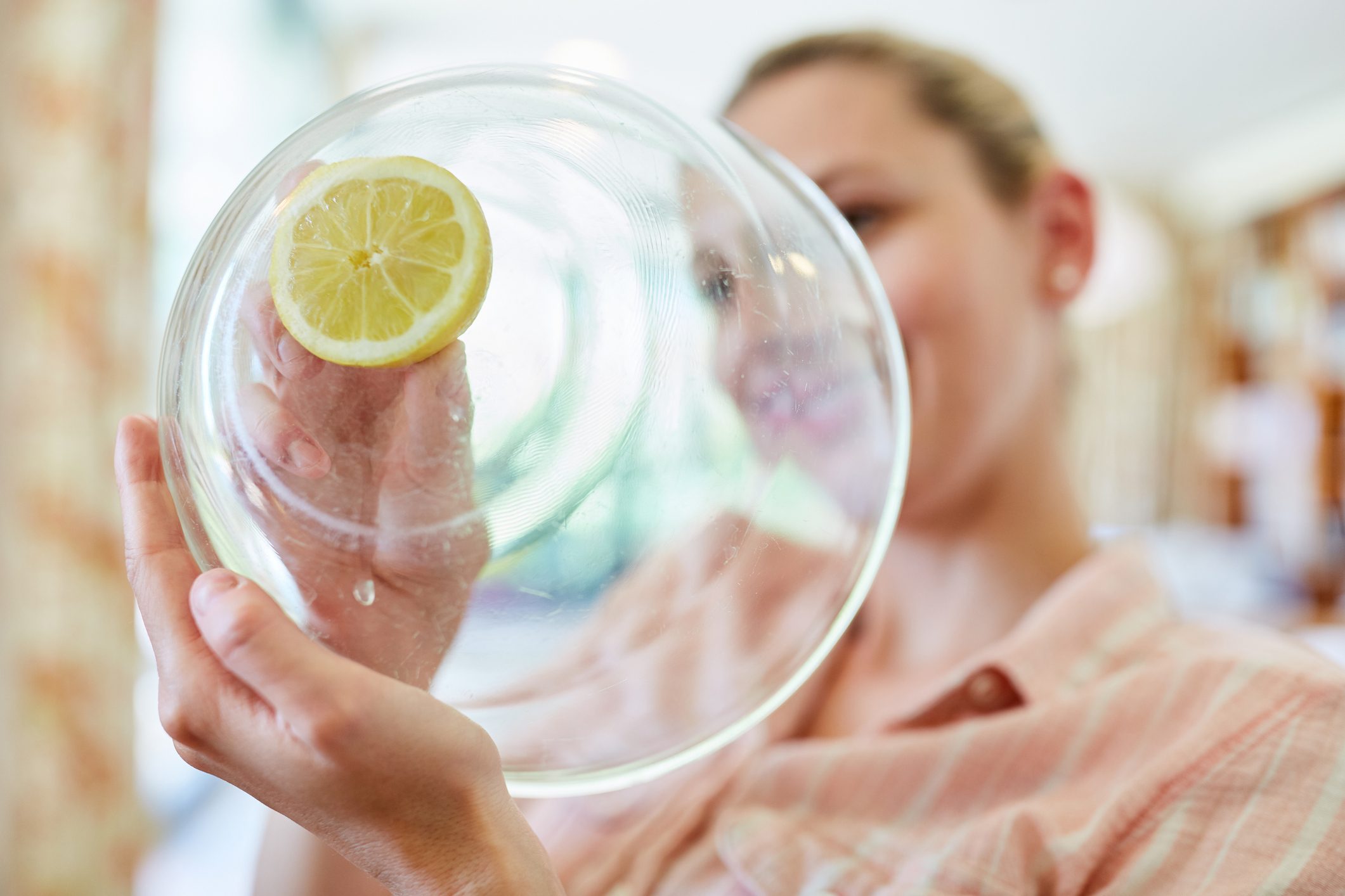 Close-Up Of Smiling Cleaning Glass Bowl With Lemon At Home