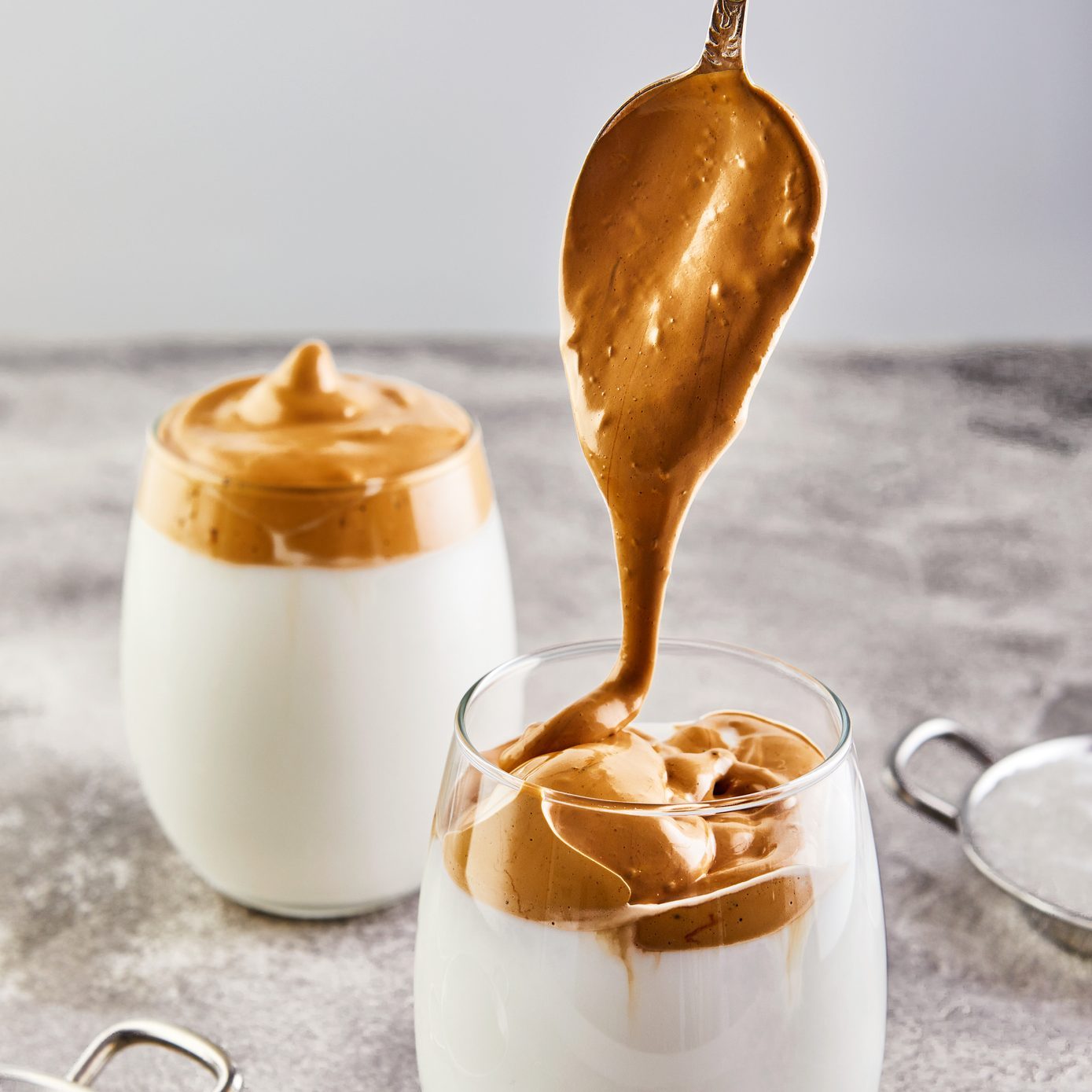 Iced Dalgona Coffee, a cool trendy fluffy whipped creamy coffee. Latte espresso with coffee foam in tall glass and milk