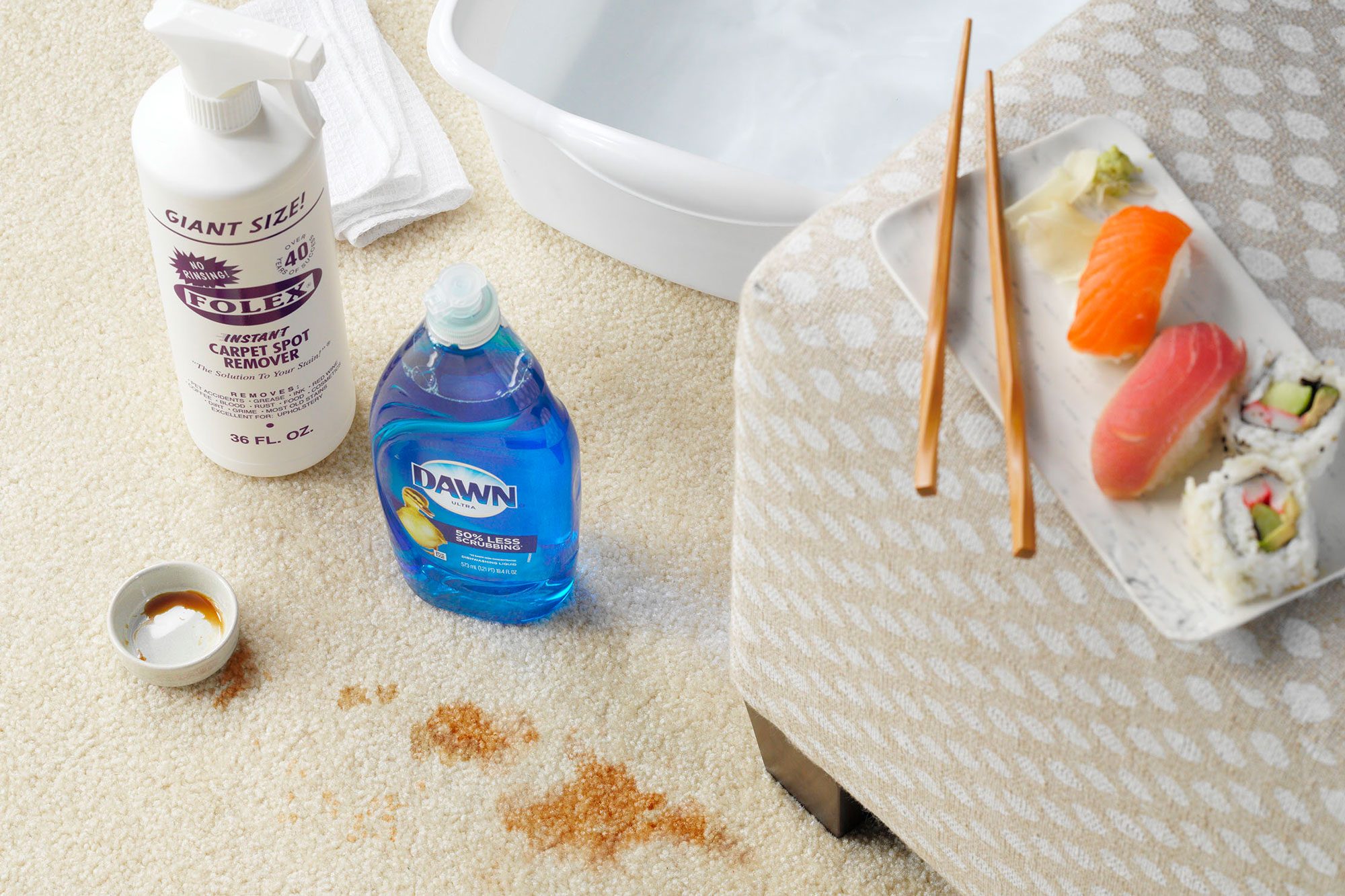 Soy Sauce stained carpet with cleaning supplies arranged nearby, sushi and chopsticks on an ottoman in the foreground