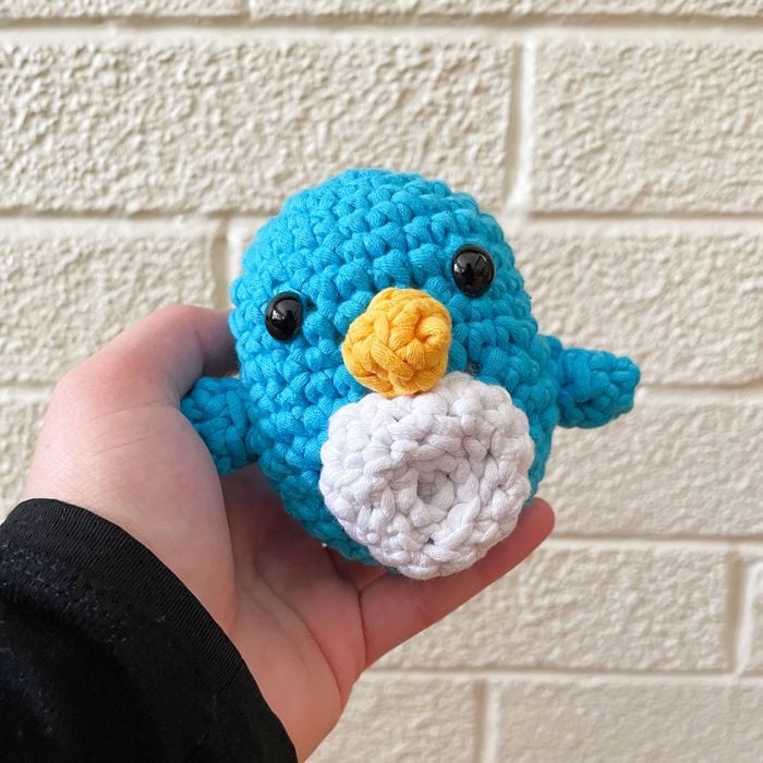 Woobles Crochet Kit finished product Pierre the Penguin being held in a person
