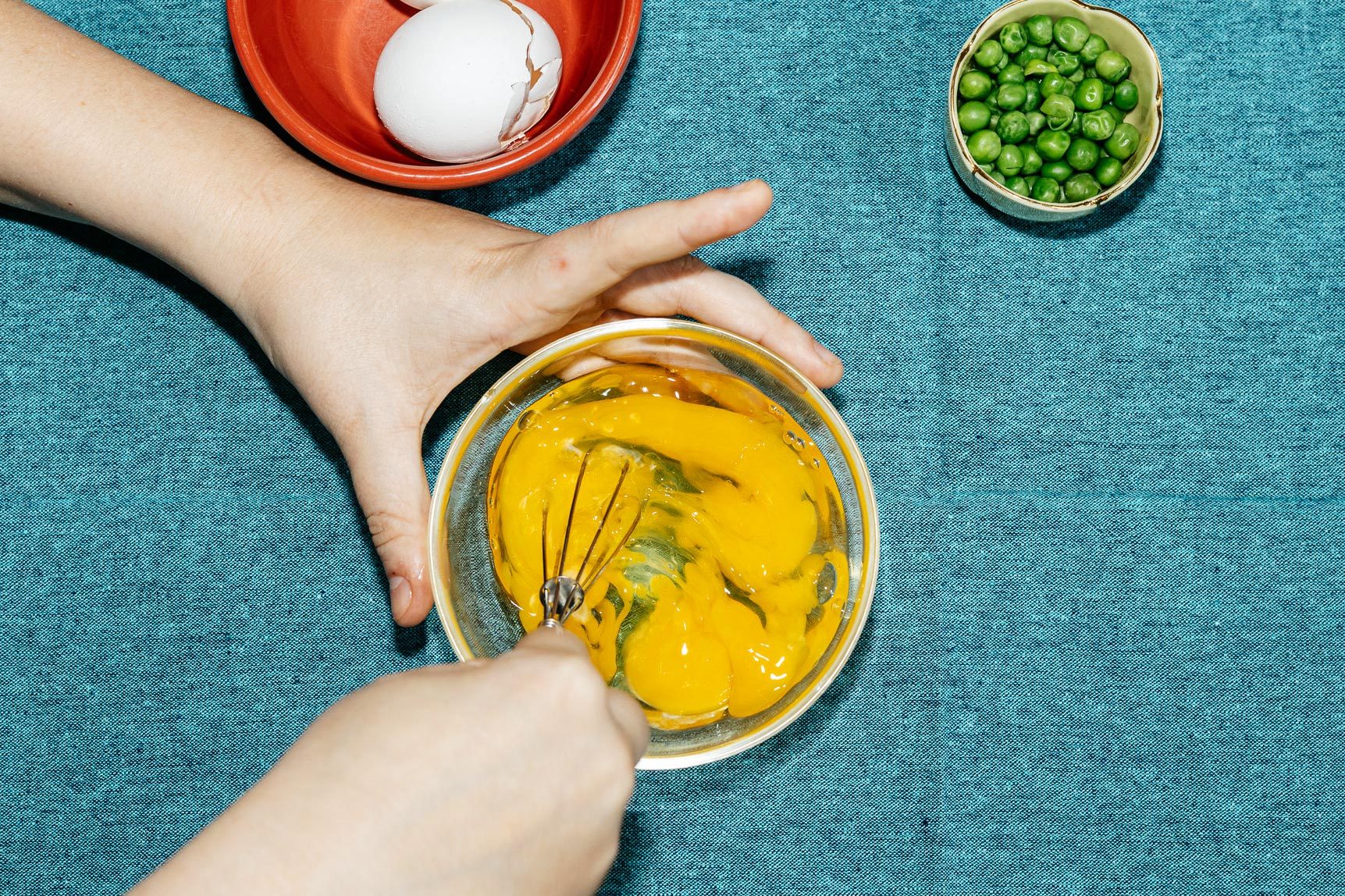 whisking an egg in a small glass bowl