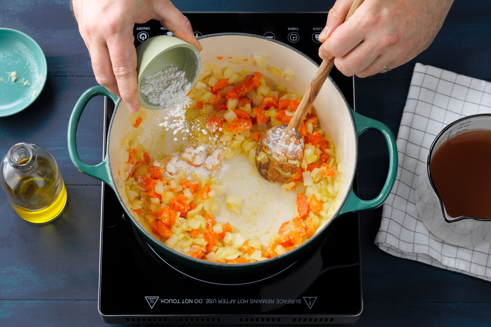 adding garlic to aromatics in soup pot on hotplate