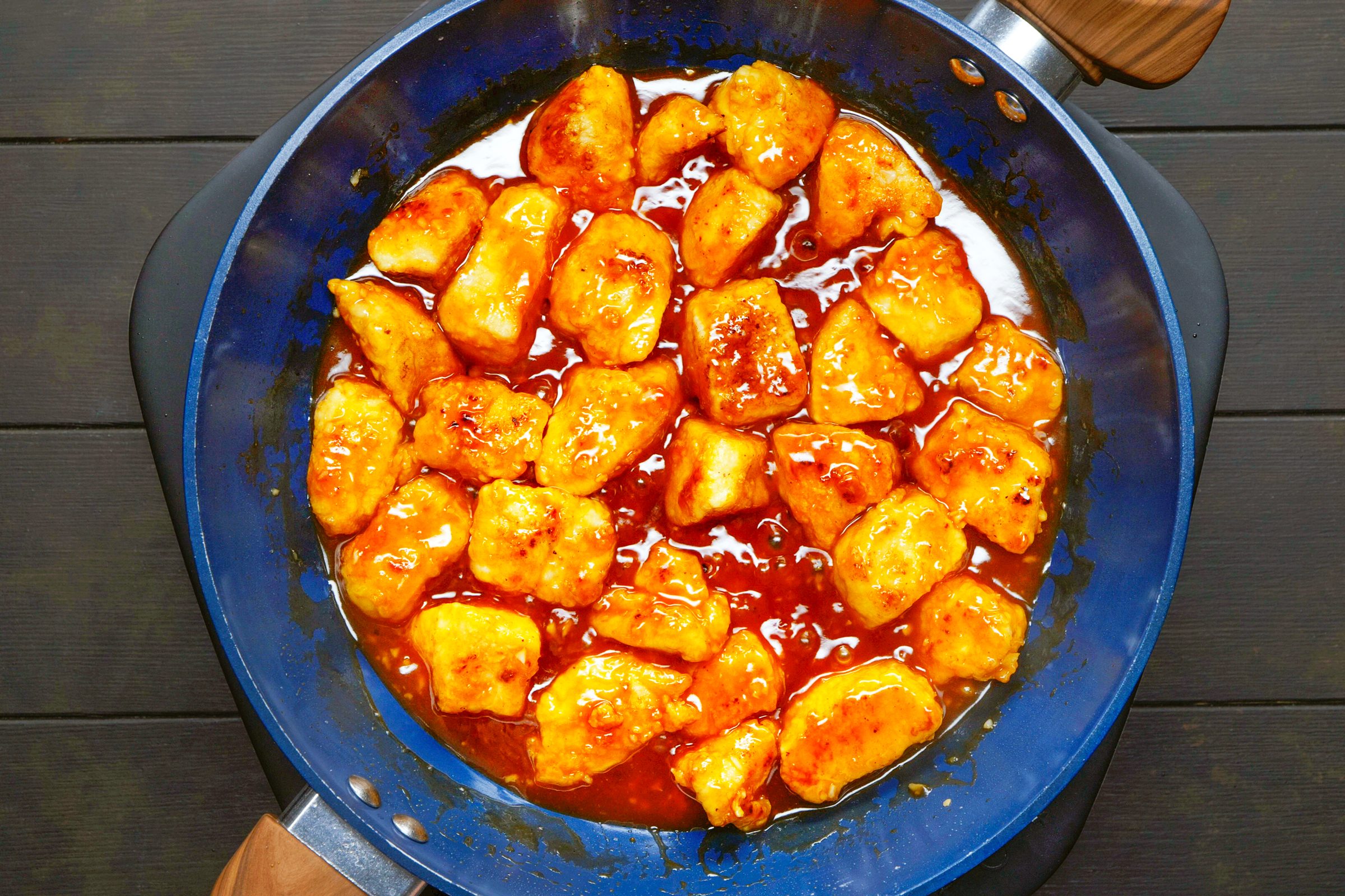 chicken coated in sesame chicken sauce in a blue pan