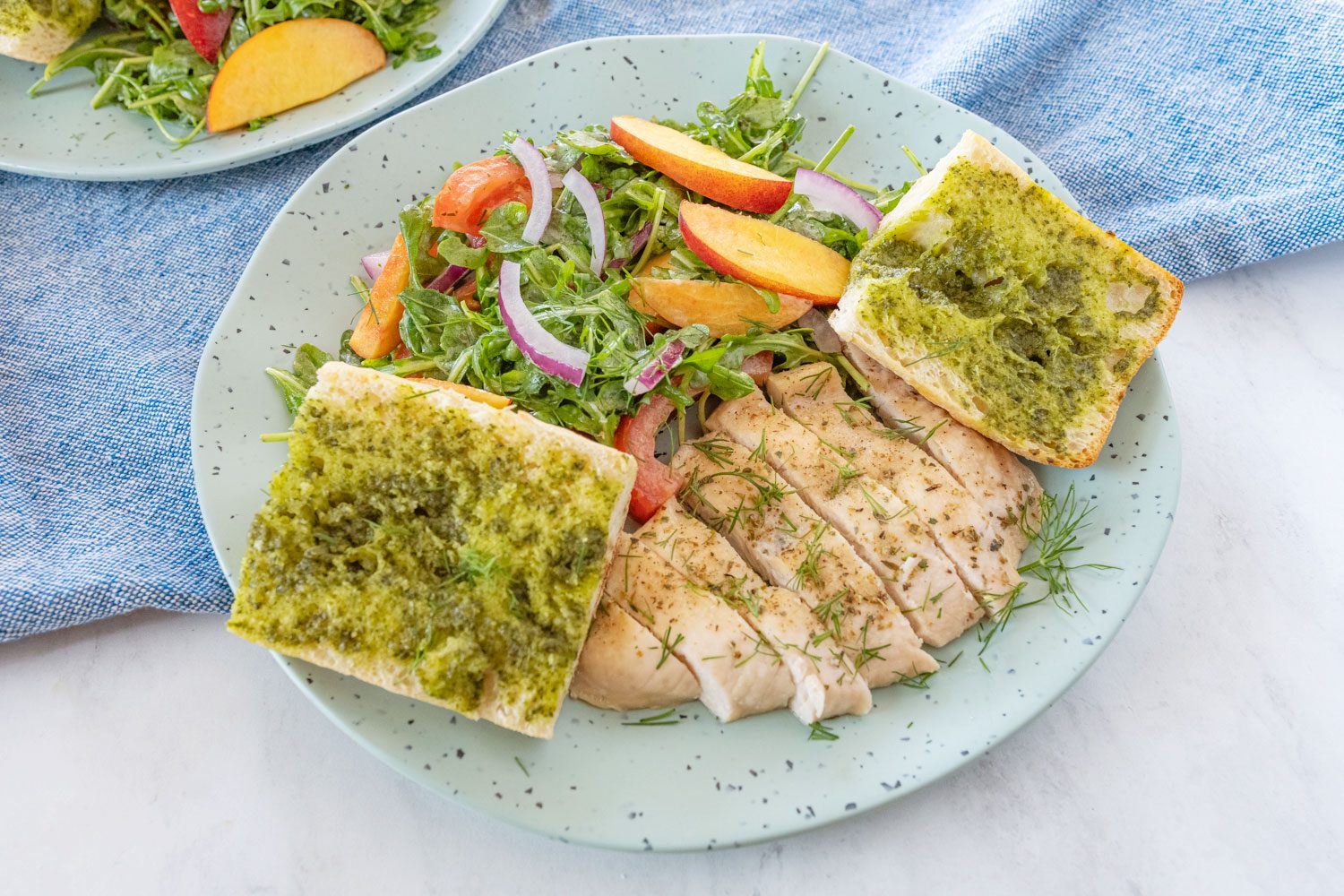 Herbed Chicken with Nectarine Summer Salad and Pesto Bread served on a plate