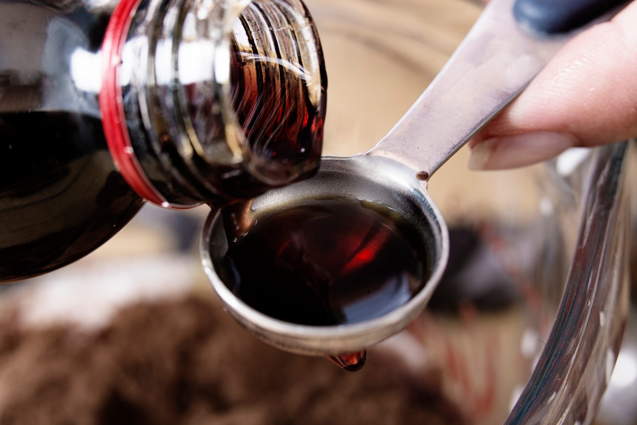 Close-up of vanilla extract being poured onto a teaspoon